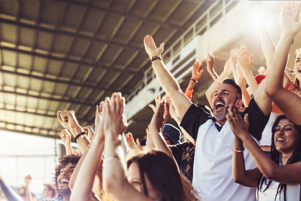 Crowd of sports fans cheering during a match in stadium.