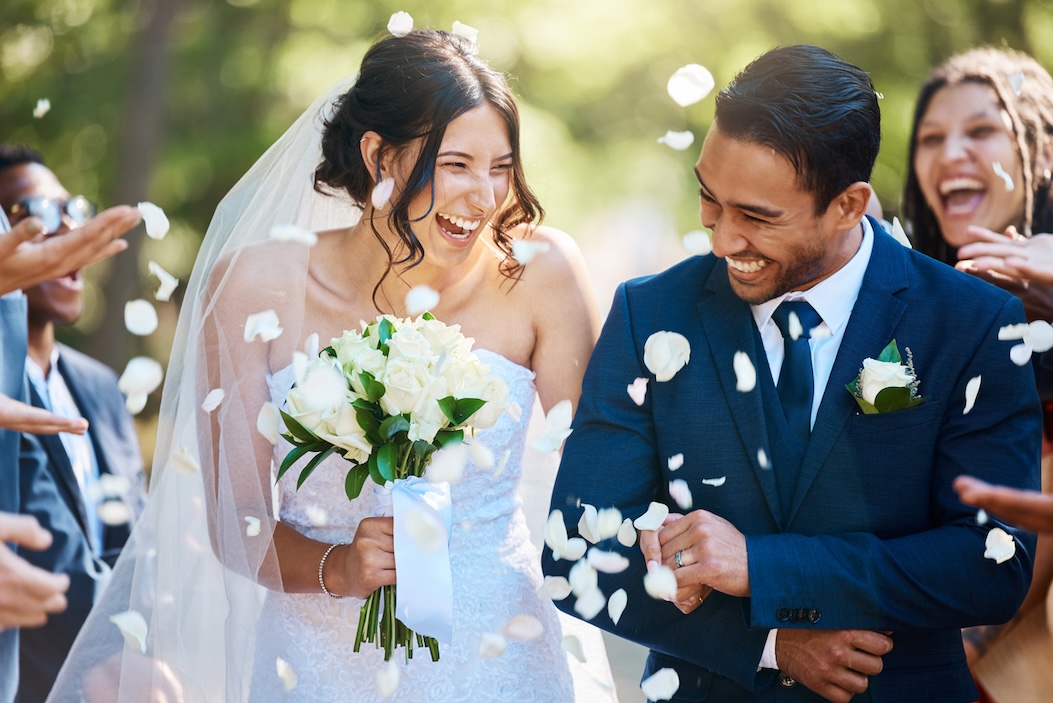 Guests throwing confetti over bride and groom as they walk past after their wedding ceremony.
