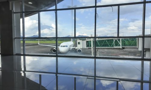 Airplane parked at an airport gate, viewed through large terminal windows.