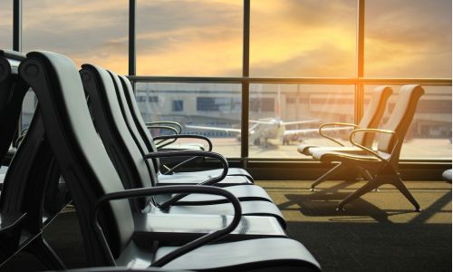 Empty chairs and passenger in the airport terminal on evening sunset light/